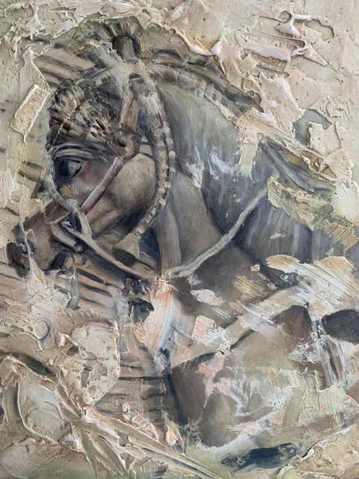 Relief sculpture of a classical horse head in profile with draped fabric, rendered in plaster or stone with weathered surface texture.