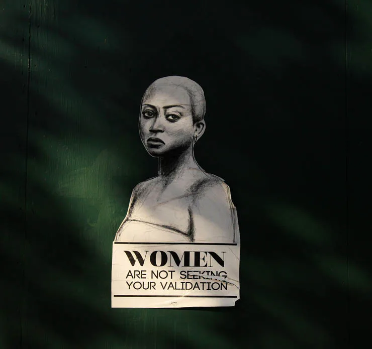 Wheat-paste street art portrait of a woman with text 'Women Are Not Seeking Your Validation'