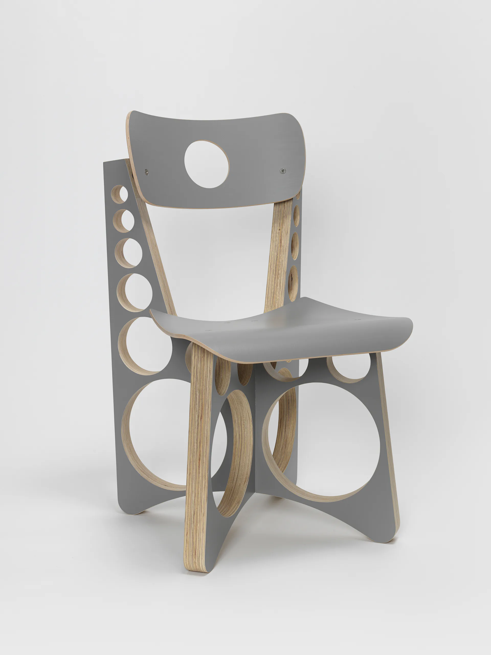 Gray and natural wood chair with circular cutouts throughout the backrest and base, featuring a molded seat and minimalist design.