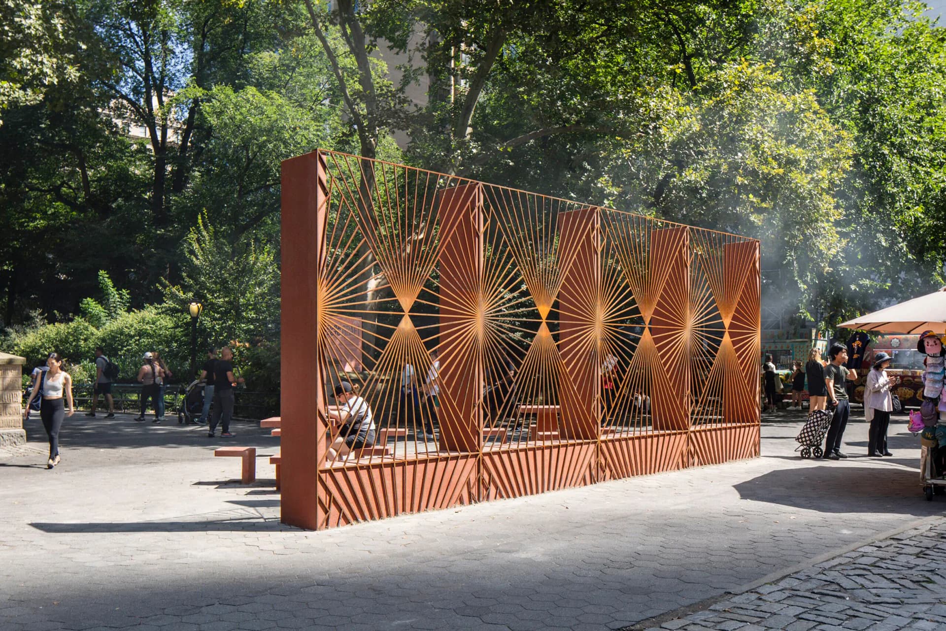 Geometric rust-colored steel installation with radiating pattern in a public park