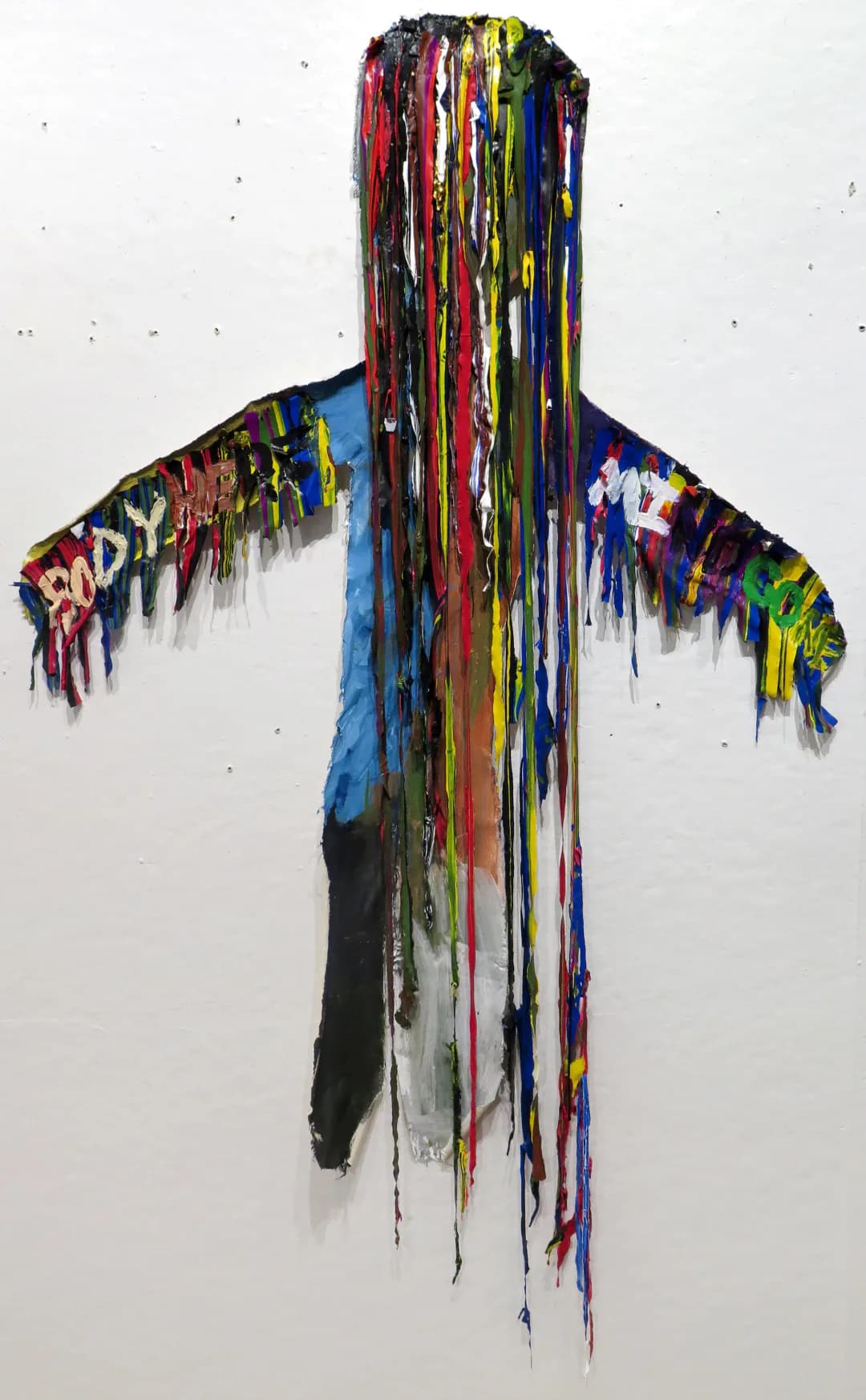 A figure-shaped silhouette on white background with head and arms dripping with strands of acrylic paint in red, yellow, blue, and black.