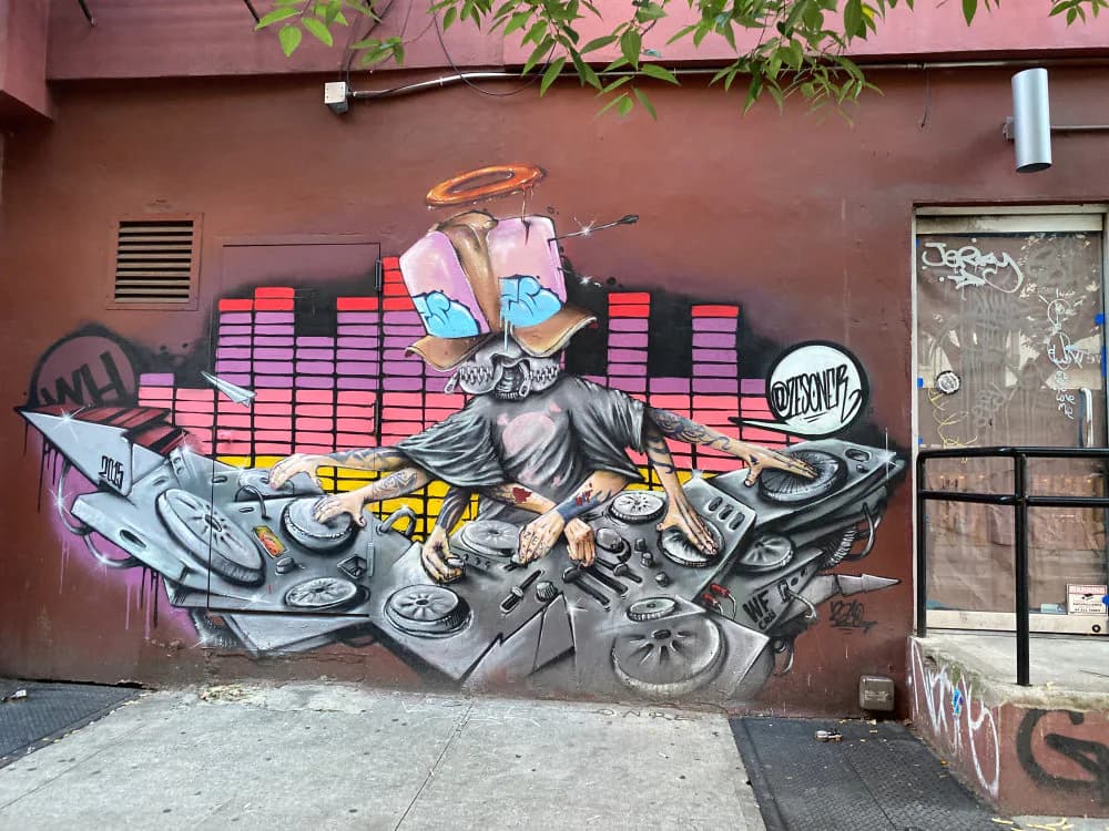 Zeso's colorful mural on a terracotta wall featuring a stylized DJ figure with turntables, pink and purple equalizer bars, and grayscale mechanical elements below.