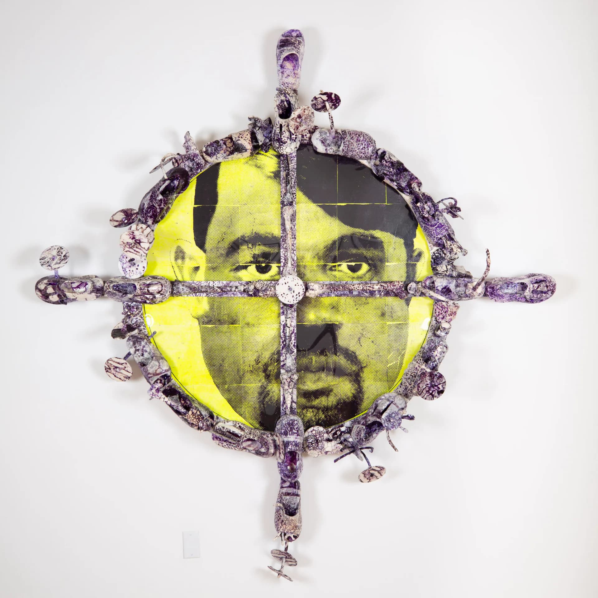 Mixed-media circular portrait with yellow and black geometric divisions, surrounded by purple textured border elements and a cross overlay.