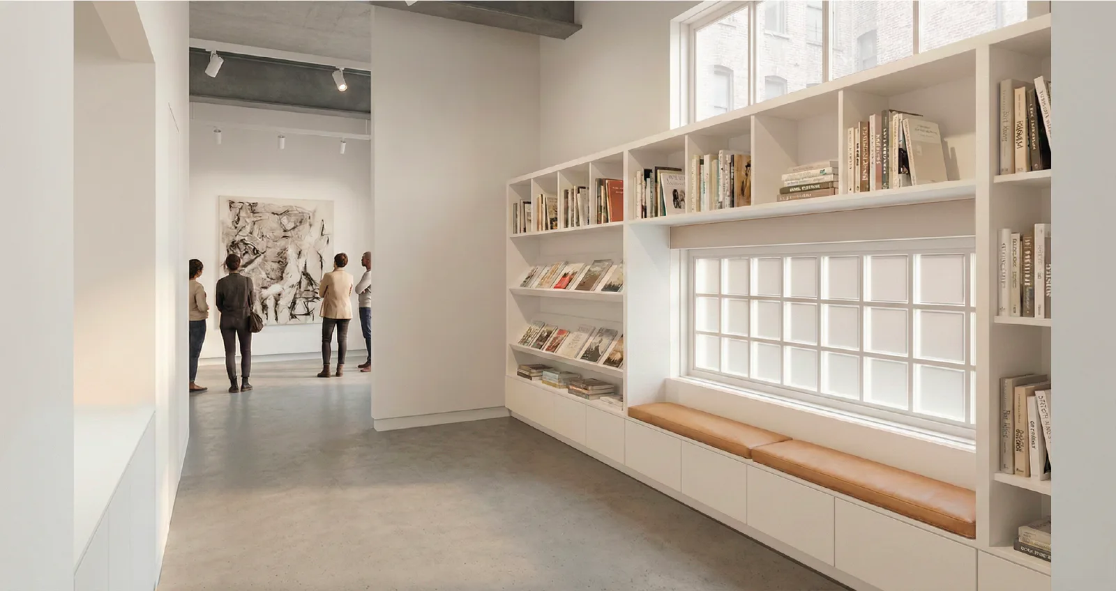 Gallery interior with built-in shelving displaying books and objects, polished concrete flooring, and visitors viewing artwork on the far wall.