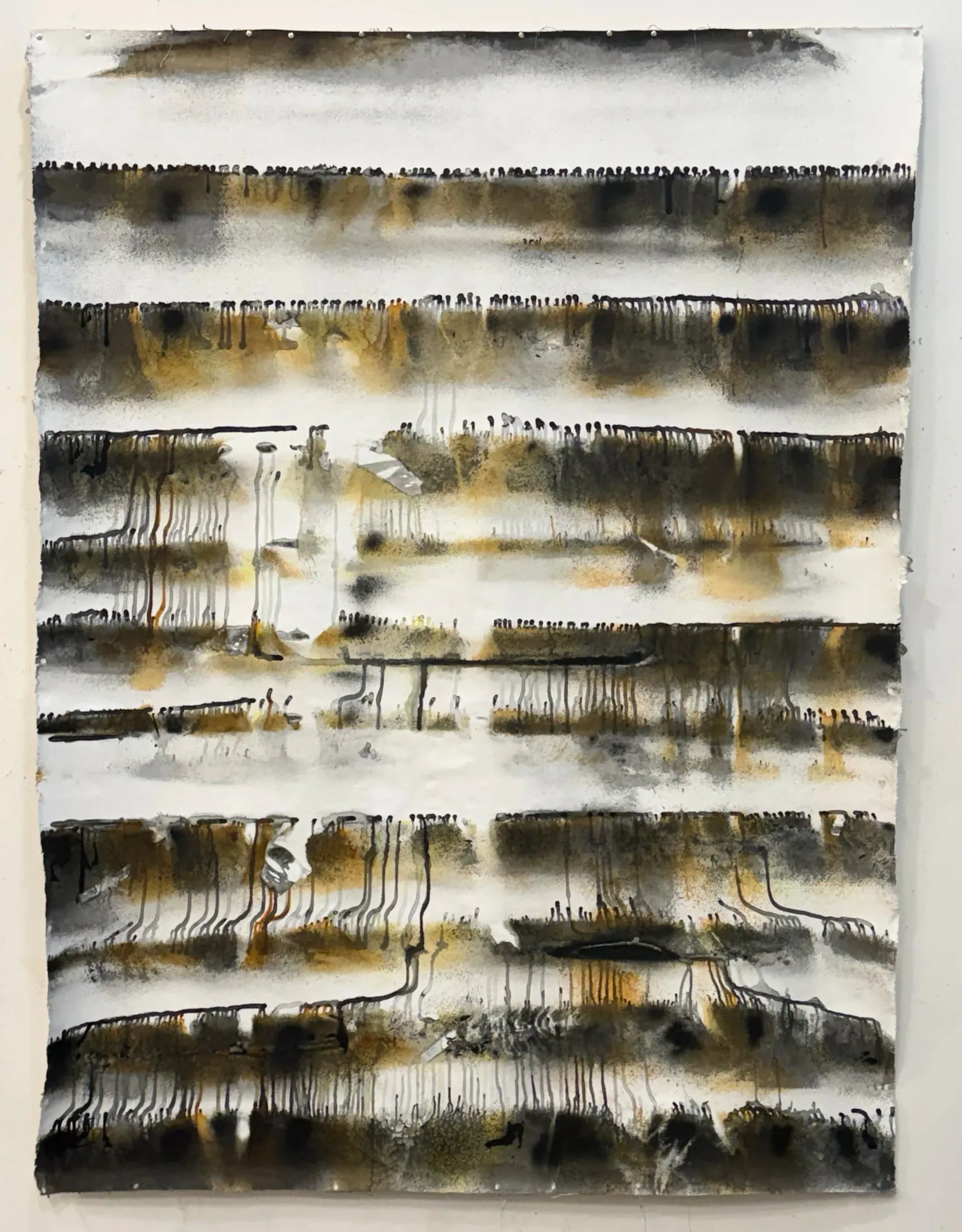 Abstract composition with horizontal bands of black charcoal marks, washes of golden and gray tones creating a layered, gestural effect on white paper.