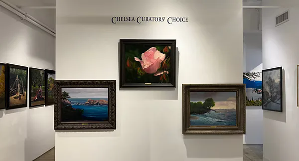 Gallery wall at Amsterdam Whitney Gallery labeled "Chelsea Curators' Choice" with framed landscape and floral artworks arranged symmetrically on white wall.