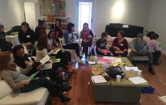 Interior photograph of Art and Resistance Through Education gallery space with people seated on couches around tables during an event.
