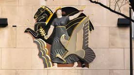 Gilded Art Deco relief sculpture of a winged, dynamic human figure in motion mounted on a light stone wall.