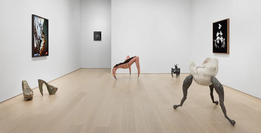 Gallery interior at Asya Geisberg Gallery with wooden floor, white walls, framed artworks, and sculptural figures in various poses throughout the space.