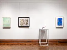 Gallery wall at Barbara Mathes Gallery displaying three framed artworks and a minimalist sculptural installation on wooden floor.