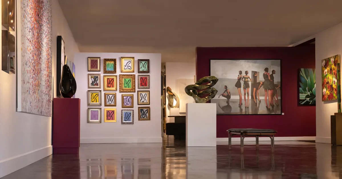Interior of Bonner David Galleries with white walls, burgundy accent walls, framed artworks, sculptures on pedestals, and polished flooring.