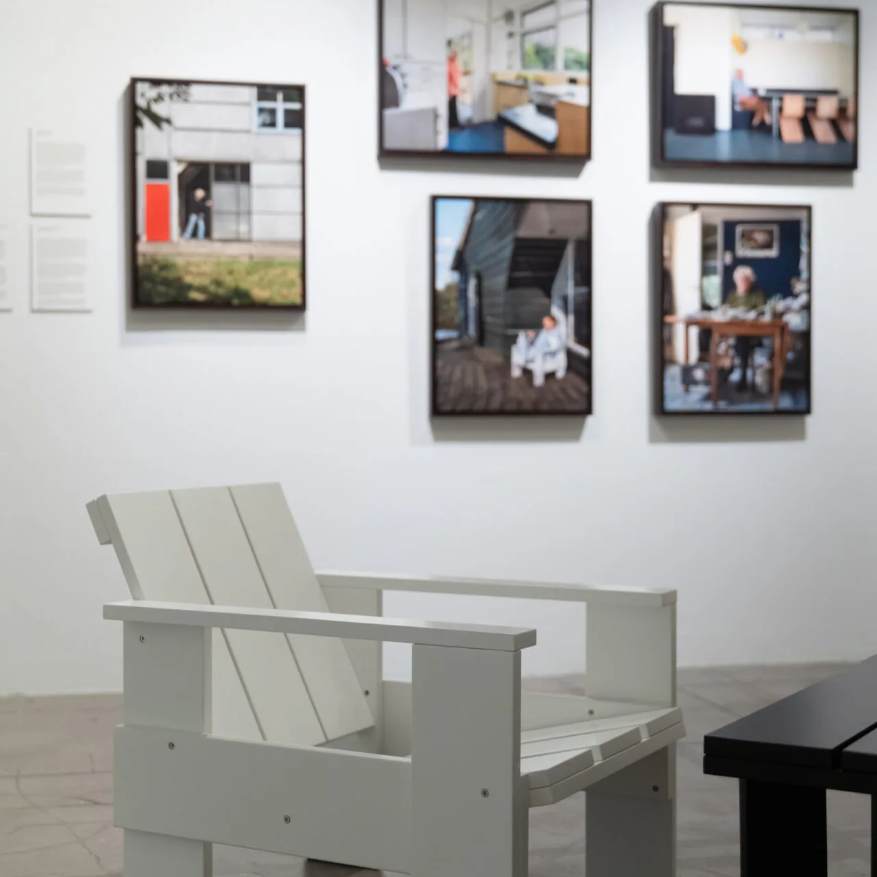 Gallery interior with five framed architectural photographs on white wall above a pale green modern chair.