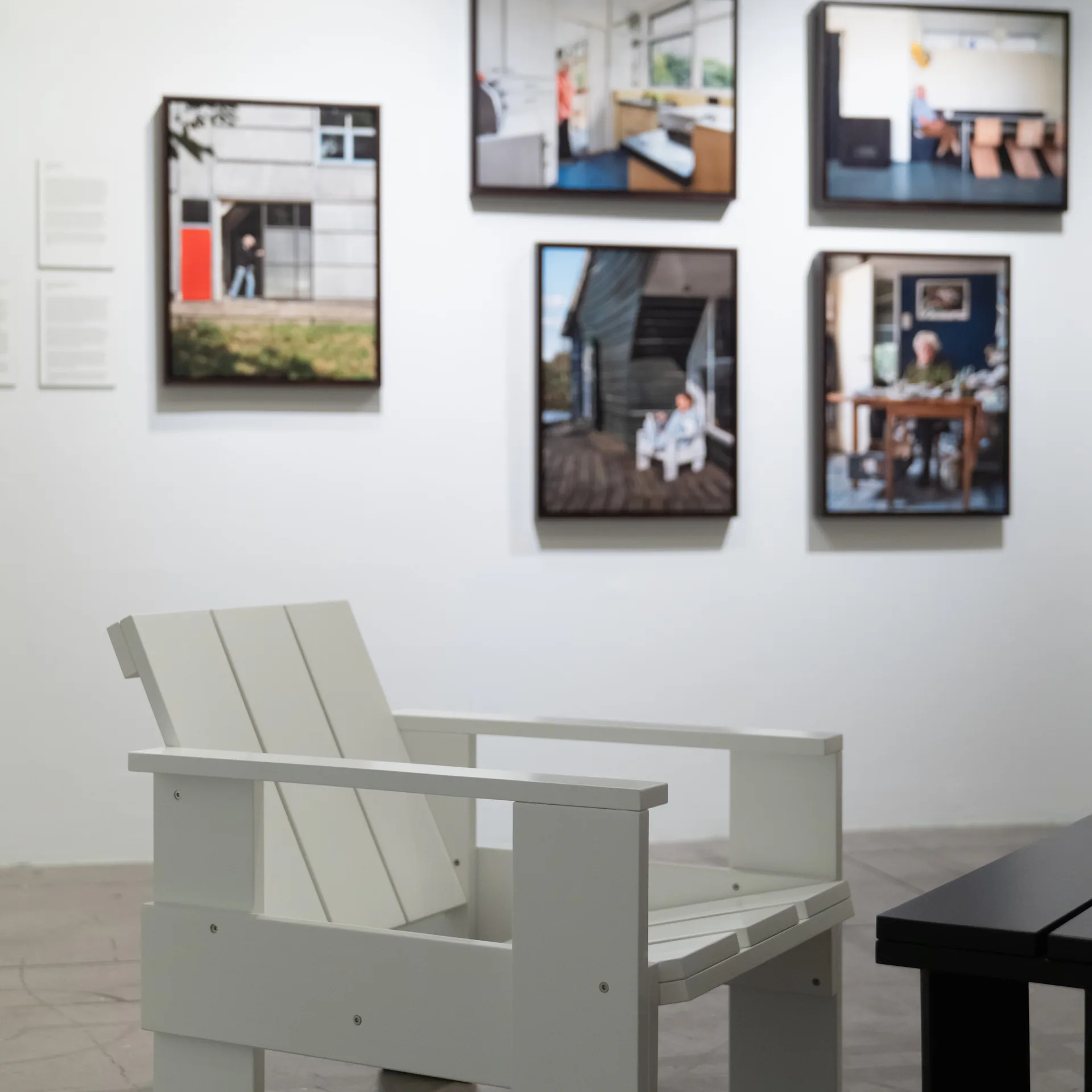 Gallery interior with five framed architectural photographs on white wall above a pale green modern chair.