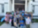 Group of adults and children posing together outside a brick building entrance at the City Island Historical Society