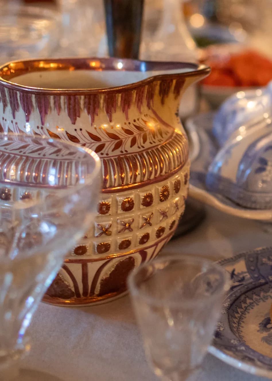 Decorative ceramic vessel with white glaze and reddish-brown geometric patterns, featuring leaf and square motifs typical of Greek or Mediterranean pottery design.