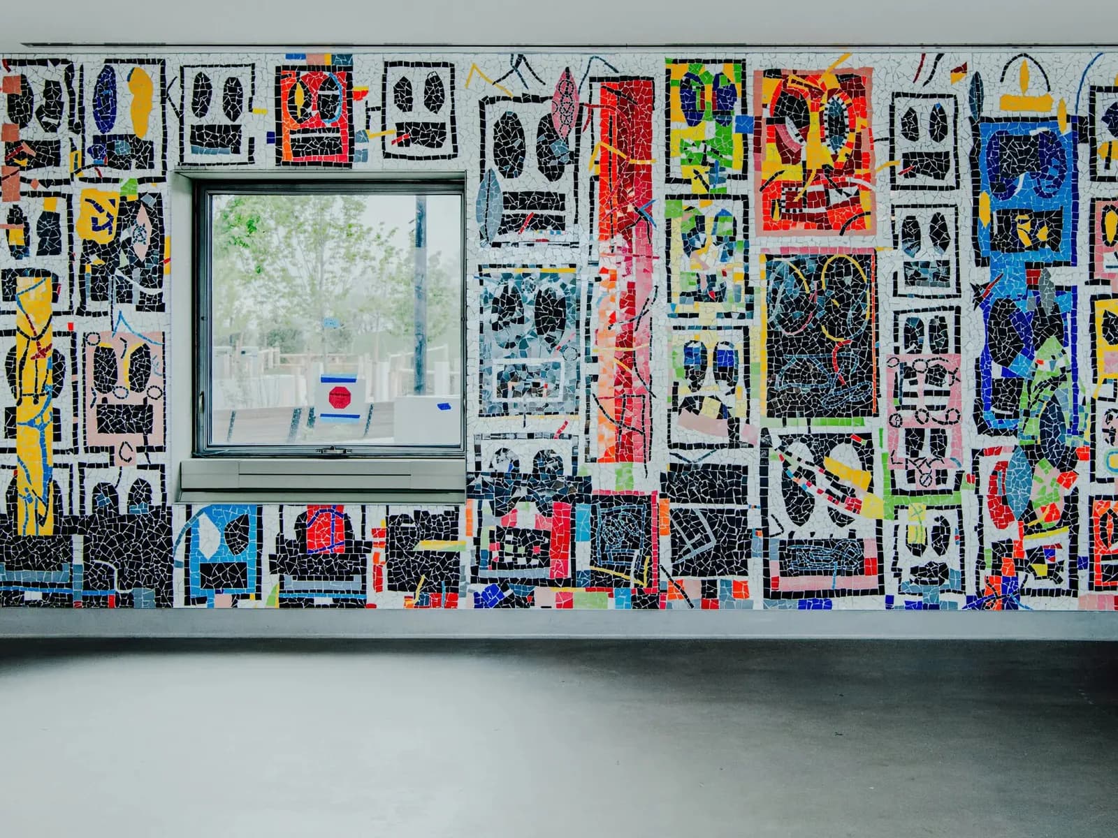 Mixed-media wall installation densely covered with colorful printed pages, photographs, drawings, and collage elements arranged salon-style.