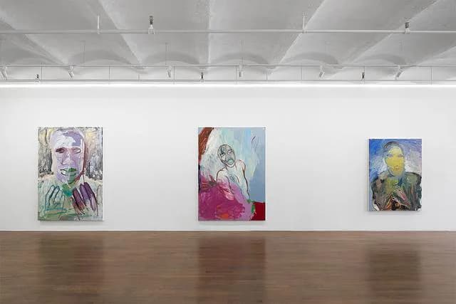 Gallery interior with polished wood floor and white walls displaying three colorful abstract paintings spaced across the space.