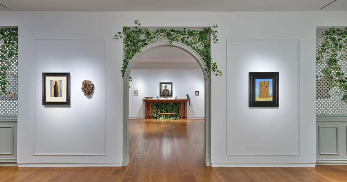 Di Donna Galleries interior with white walls, arched doorway, framed artworks on either side, and decorated fireplace mantel visible through arch.