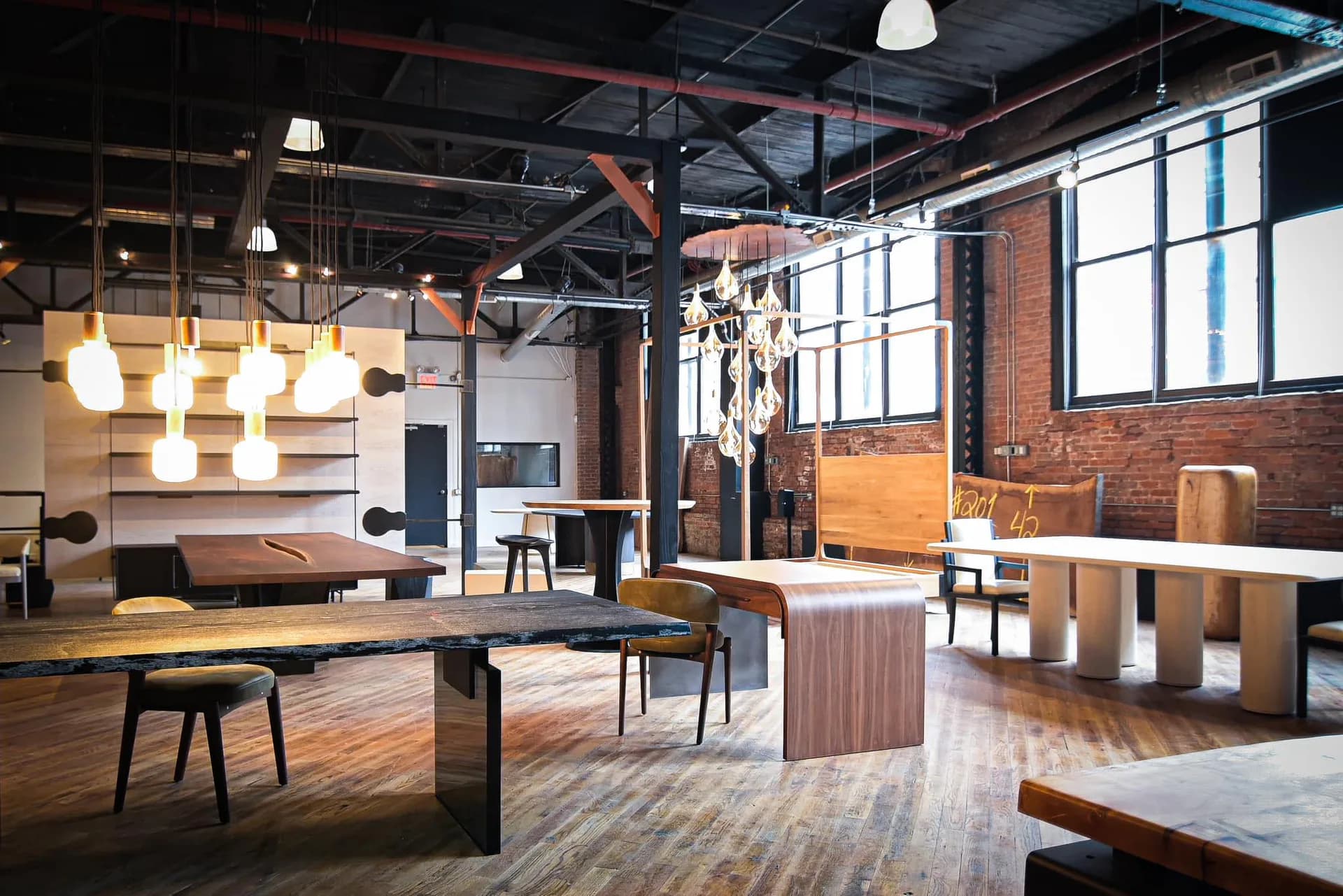 Industrial loft space with exposed brick, wooden furniture, hanging pendant lights, and concrete floors.