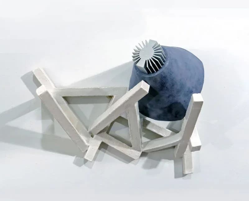 Abstract sculptural installation with white geometric wooden framework and a dark blue spherical form topped with a radiating fan-like element.