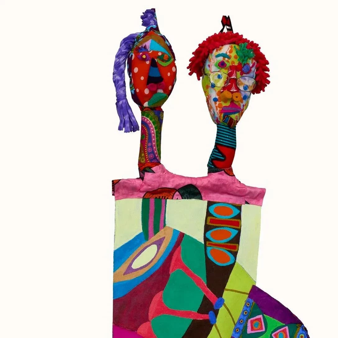 Mixed-media sculptural figures with colorful patterned heads and bodies in vibrant jewel tones, displayed on a geometric base.