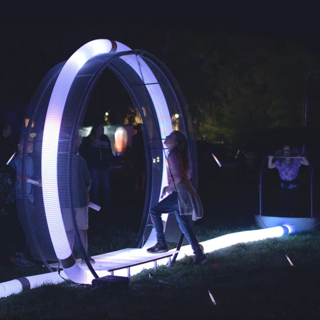 Nighttime photograph of an interactive light installation at Everything Good Studio featuring luminous curved arches with a person walking through.