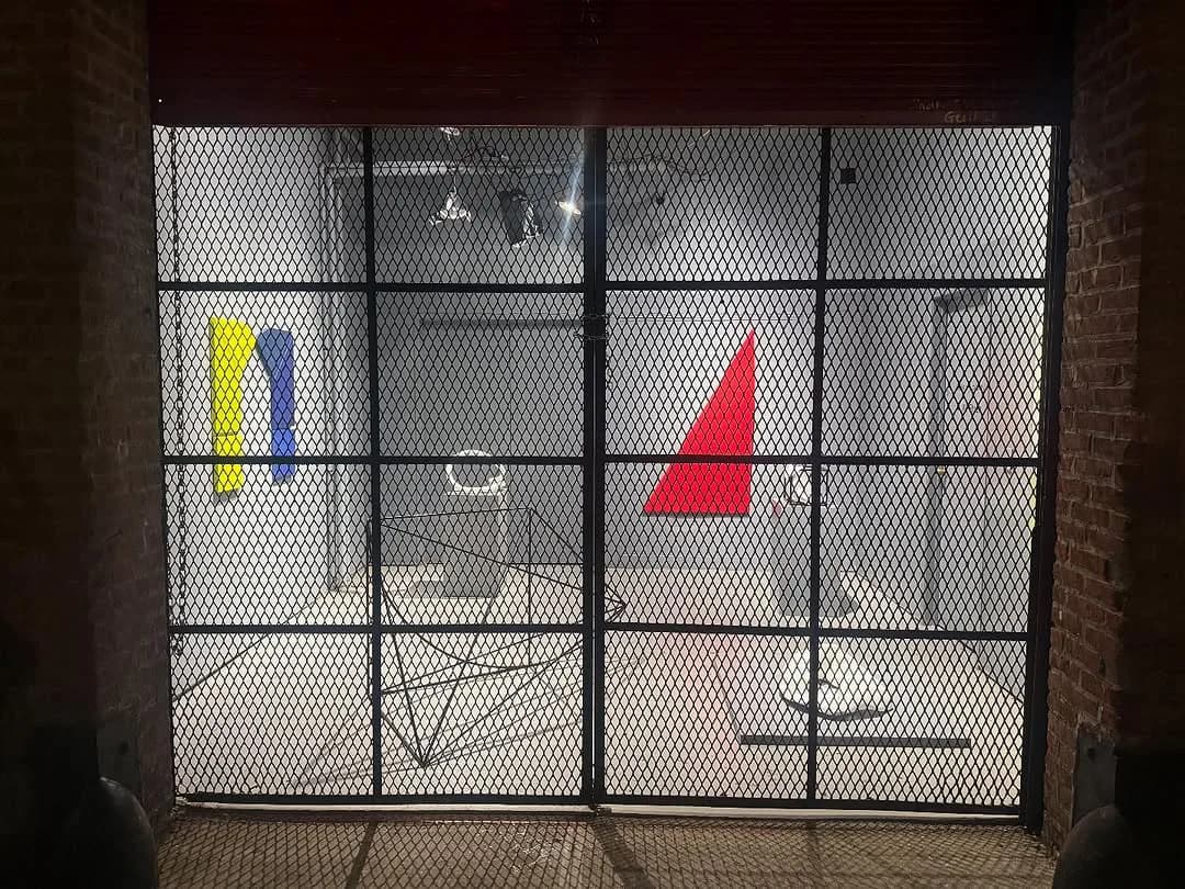 FiveMyles storefront with black mesh gate displaying geometric red and blue-yellow artworks visible through the window.