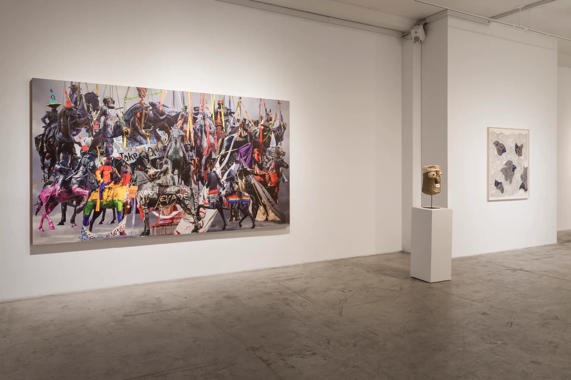 Minimalist gallery interior with polished concrete floor, white walls, and colorful abstract paintings displayed with sculpture on pedestal.