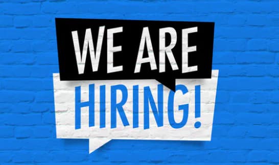 Blue brick background with black and white speech bubble containing "WE ARE HIRING!" in bold white and blue lettering.