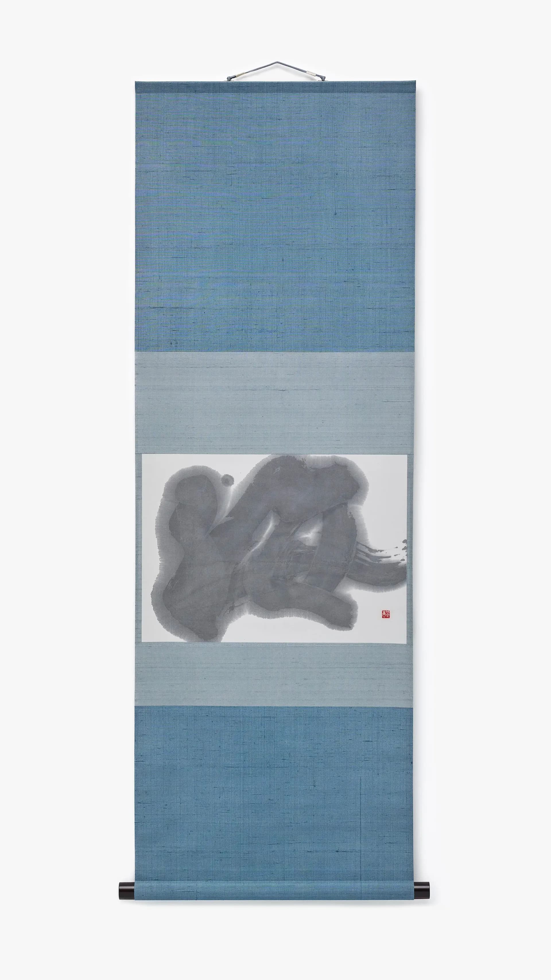 Vertical scroll painting with blue linen-textured panels framing a centered ink-wash figure study in grayscale depicting reclining figures.