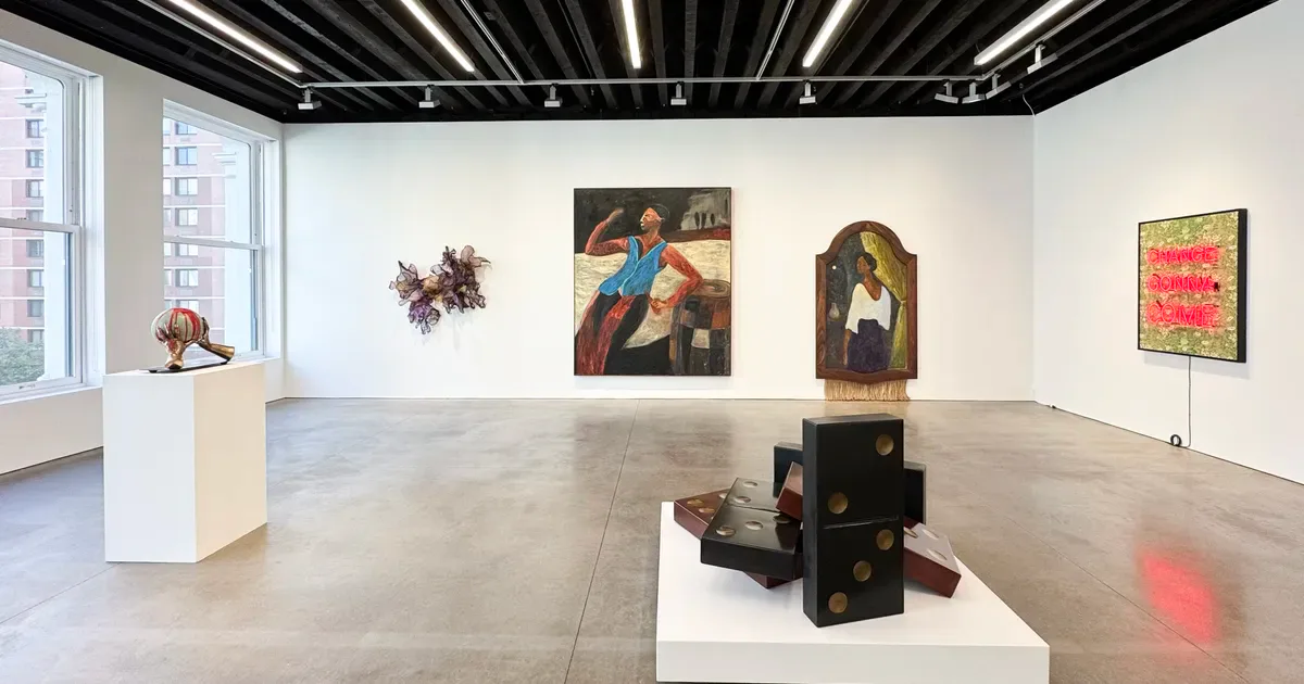 Gallery interior with white walls, black ceiling track lighting, large windows, multiple paintings and sculptures displayed including religious artwork and a sculptural form on white pedestal.