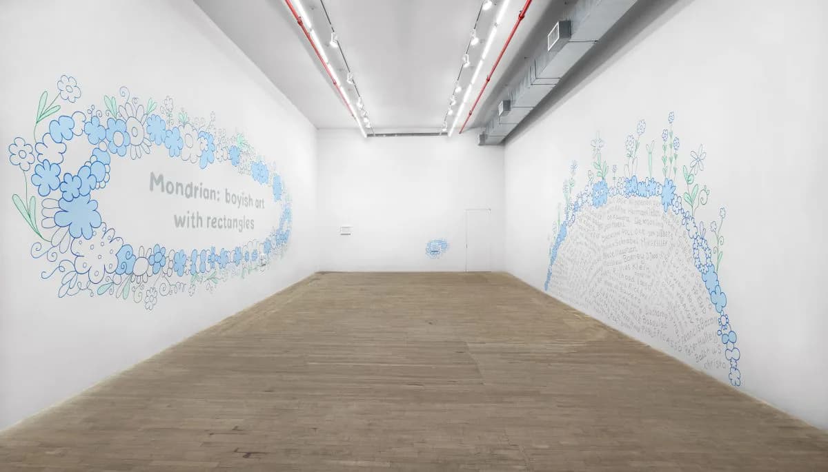 Kaufmann Repetto gallery interior with light wood flooring, white walls, skylights, and blue hand-drawn wall installations on multiple walls.