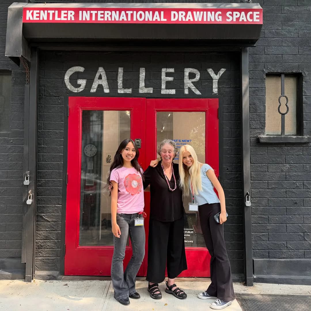 Red storefront entrance of Kentler International Drawing Space gallery with three people posing at the doorway.