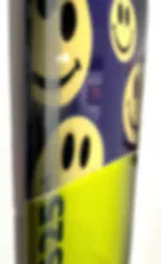 Cylindrical object with fluorescent yellow-green and purple sections decorated with smiley face motifs.
