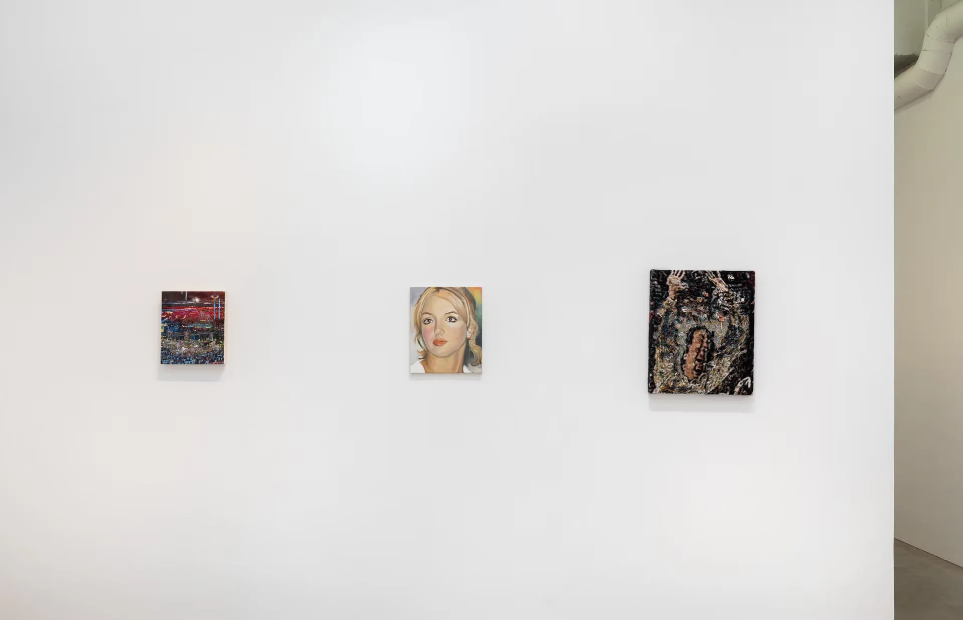 Kravets Wehby Gallery white wall displaying three small mixed-media works: abstract compositions, a portrait, and textural pieces spaced across the wall.