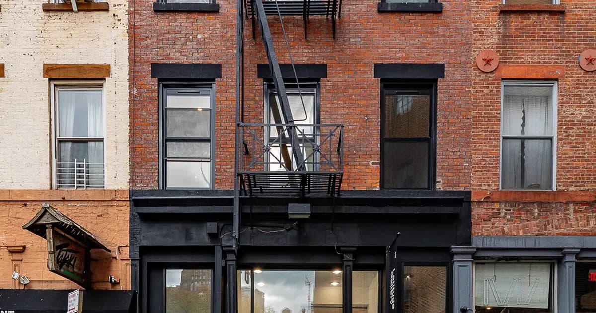 Exterior brick facade of Latitude Gallery storefront with black trim, fire escape, and glass entrance doors