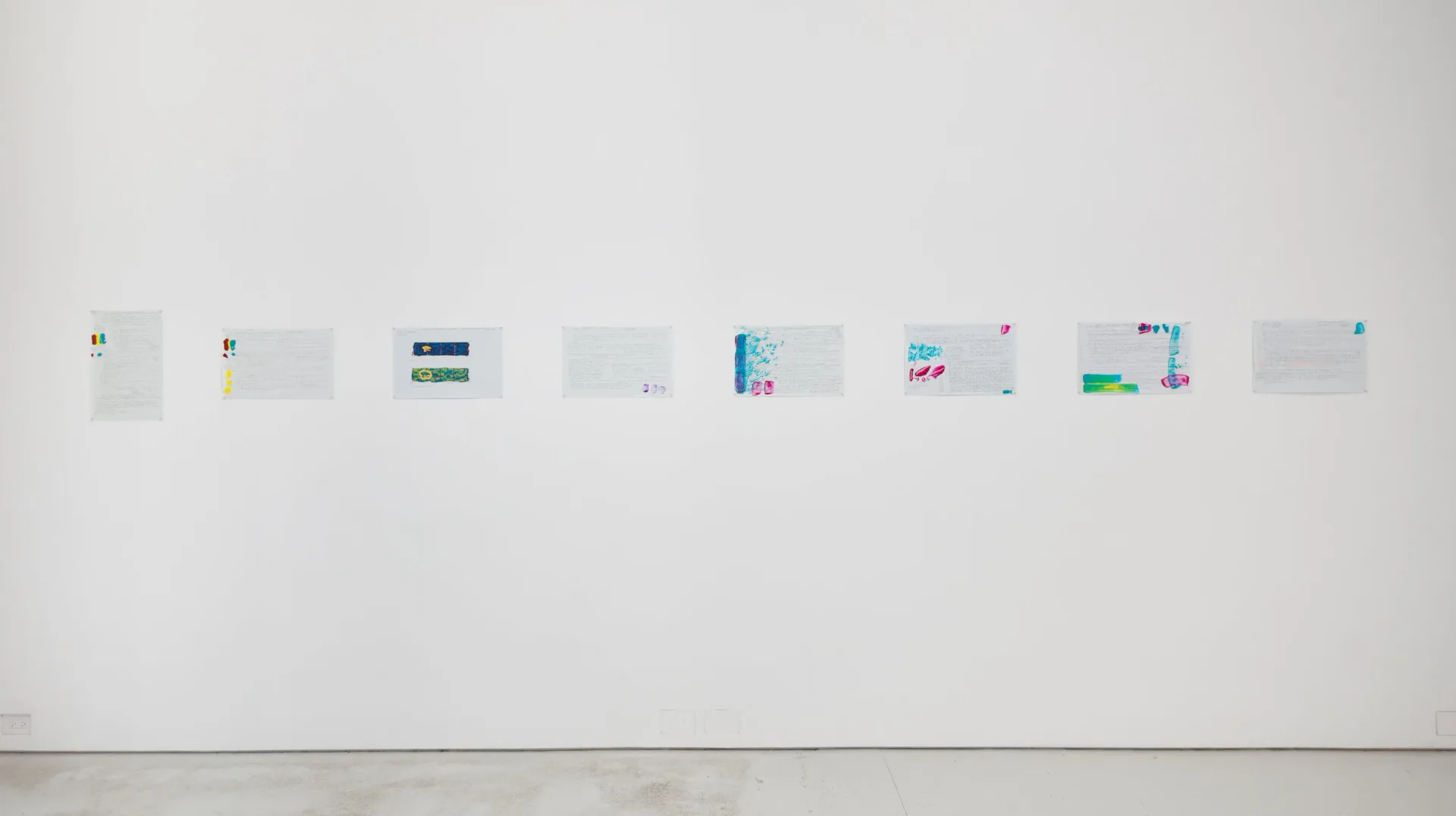 Gallery wall displaying eight small framed artworks arranged in a horizontal line.