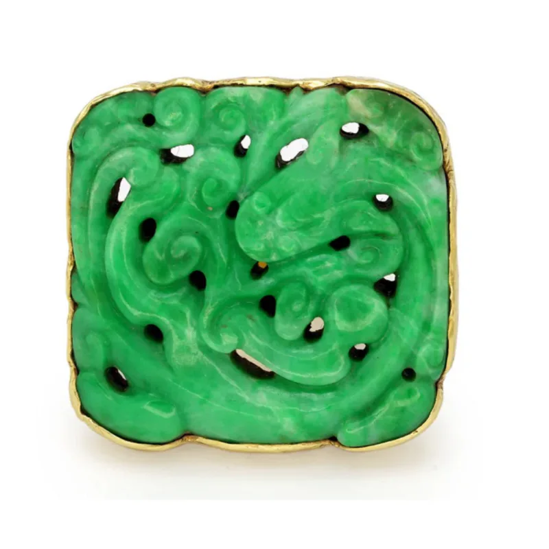 Square jade carving with gilt bronze border, featuring green jadeite with scrolling relief patterns and black and white inlay details.