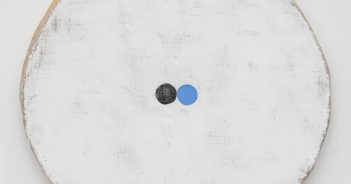 Mixed-media work on textured white circular background with two small spheres—one dark gray and one blue—positioned in subtle composition.
