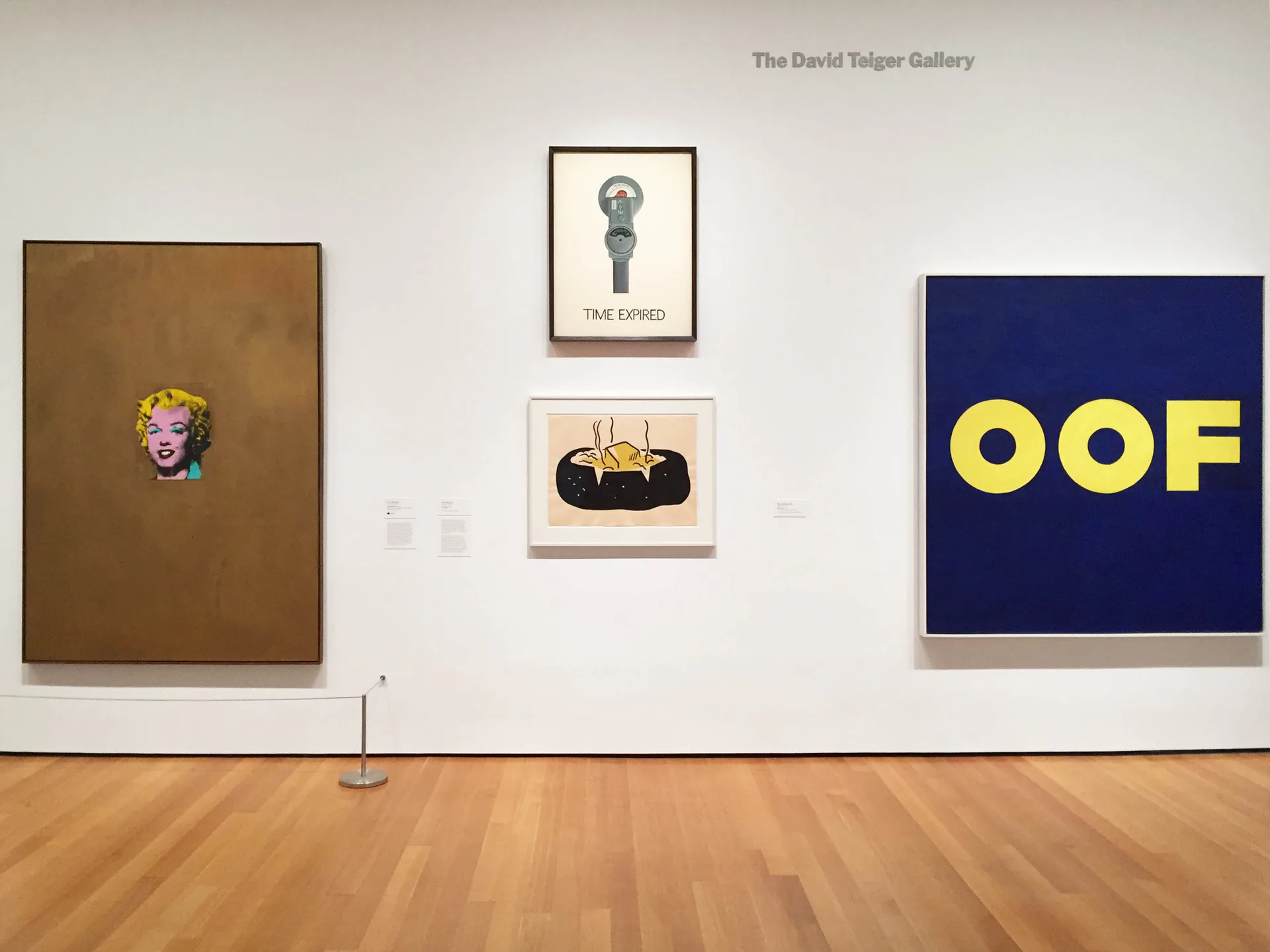Gallery wall at Maxwell Graham / Essex Street with brown canvas left, central framed drawing, and blue canvas with yellow 'OOF' text right.