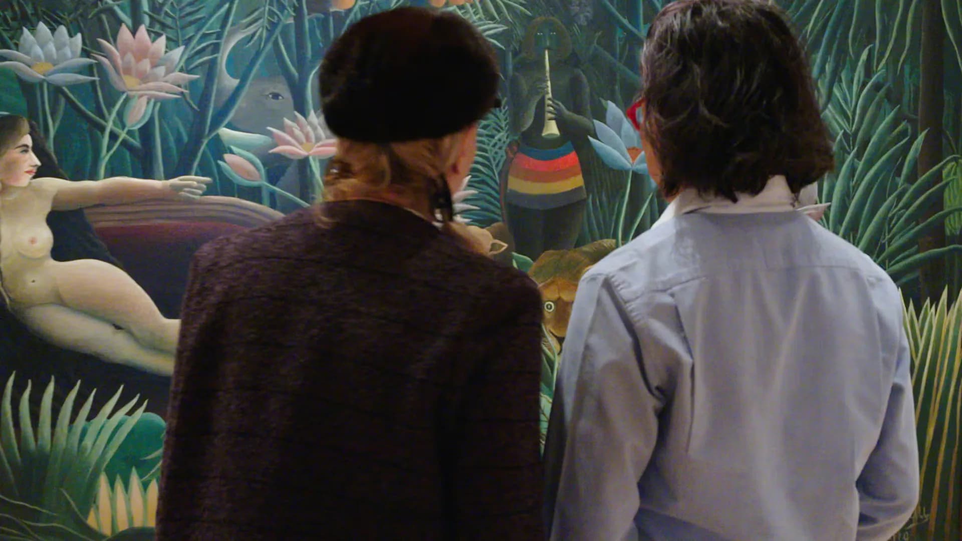 Two visitors from behind viewing a colorful tropical jungle mural artwork with water lilies and vegetation.