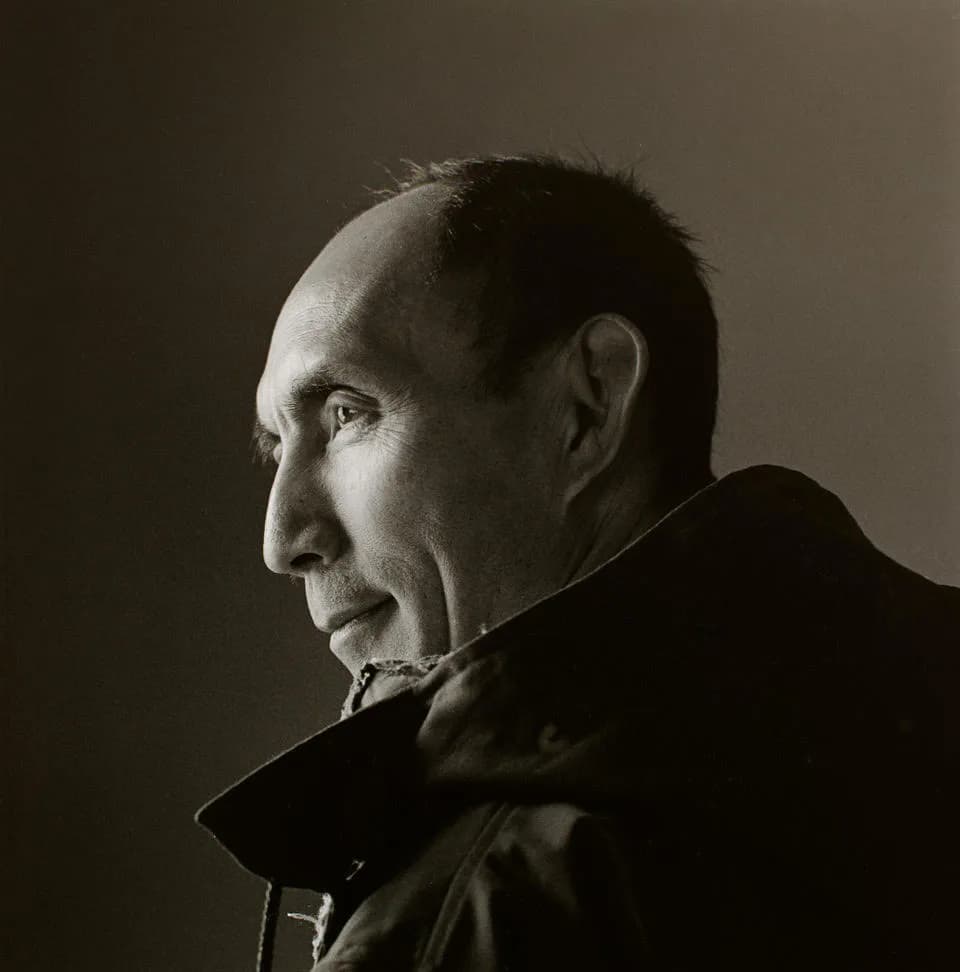 Black and white profile portrait of an older man in formal dark clothing against a neutral background.