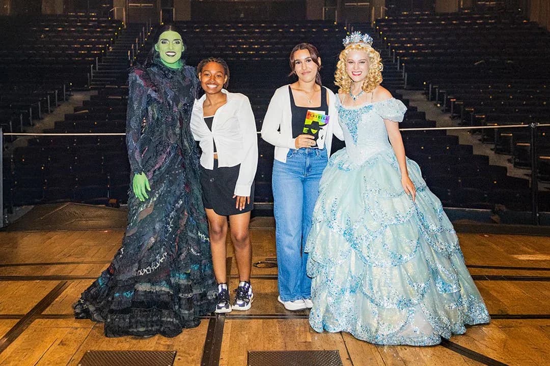 Four people in costume posing on a theater stage, including figures dressed as the Wicked Witch and Cinderella characters.