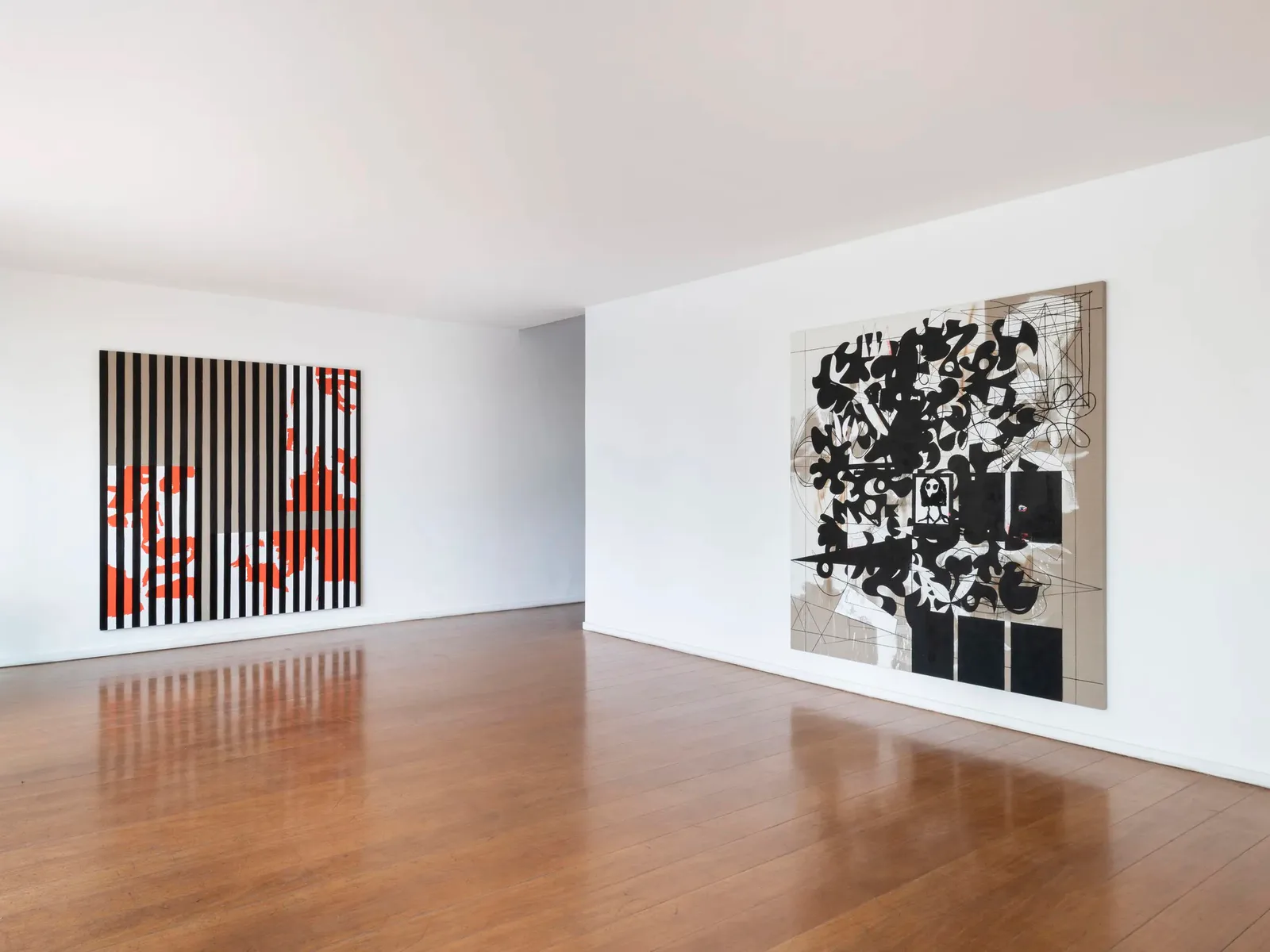 Gallery interior with white walls and wood floors displaying two large abstract paintings