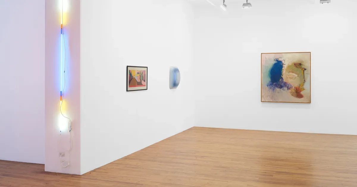 Gallery corner with wooden floor, white walls, neon light installation on left pillar, and three framed artworks including blue abstracts and watercolors.