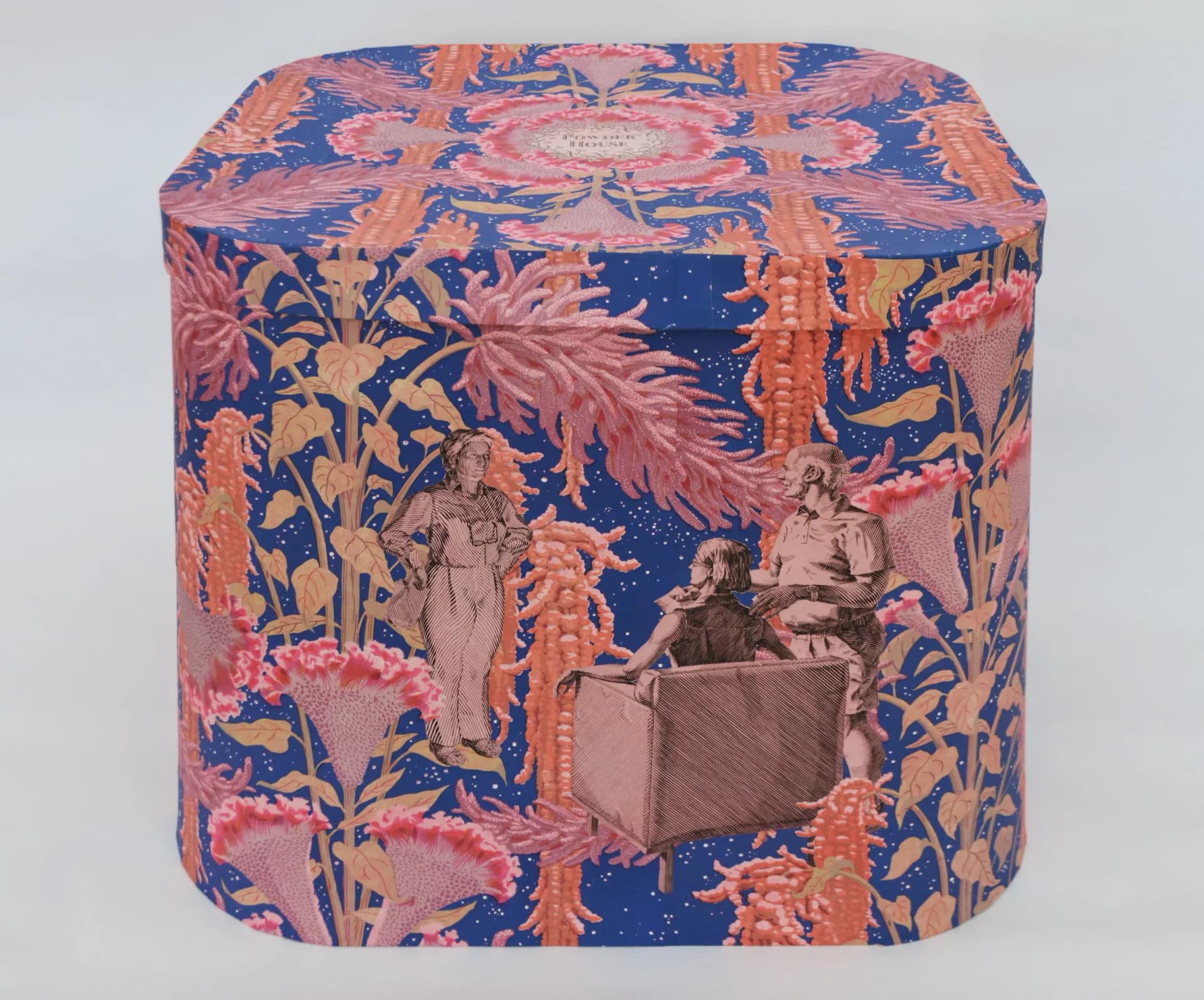 Cylindrical decorative box covered in ornate blue and coral patterned textile with classical figurative scenes and geometric borders, traditional craft style.