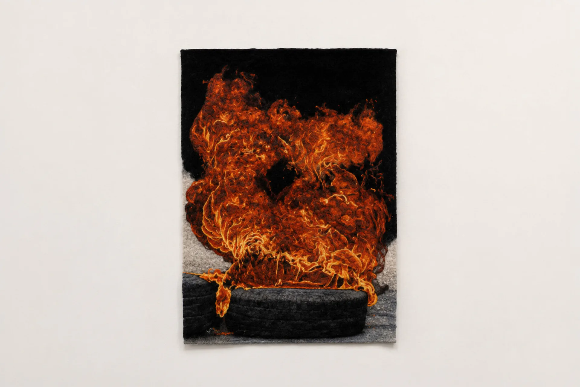 Photograph of intense orange flames erupting from a burning tire against a black background, mounted as a framed print.