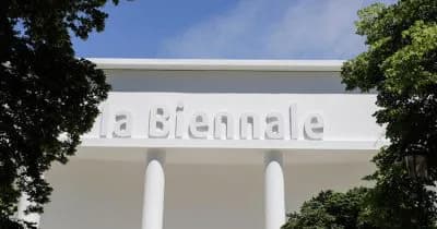White modernist building exterior with 'a biennale' text on facade, framed by green climbing vines and two white columns.