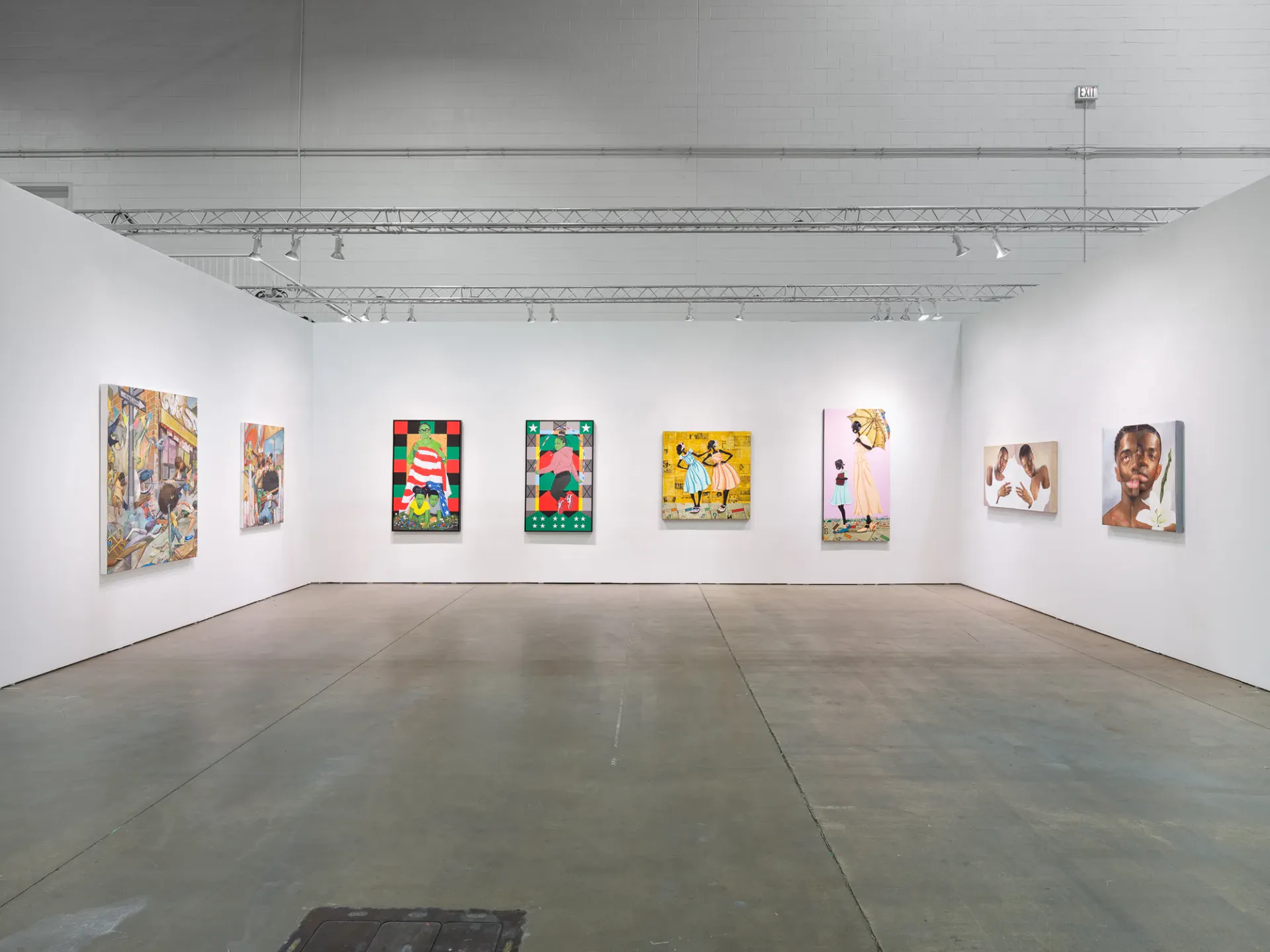 White-walled gallery space with gray concrete floor showing the same eight artworks hung on back wall, with industrial ceiling and track lighting.