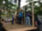 People gathered on an outdoor wooden platform surrounded by trees at an RPGA Studio event